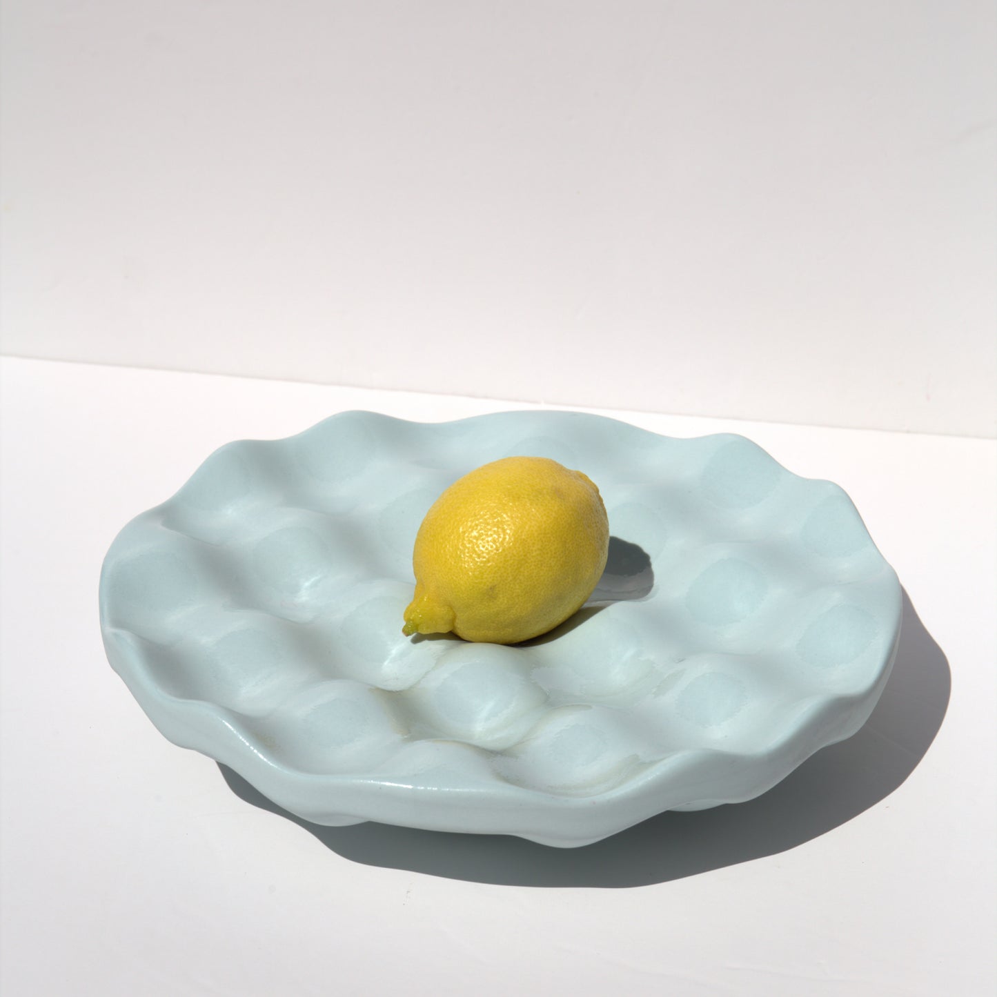 Dune Bowl Light blue with a lemon on a white background
